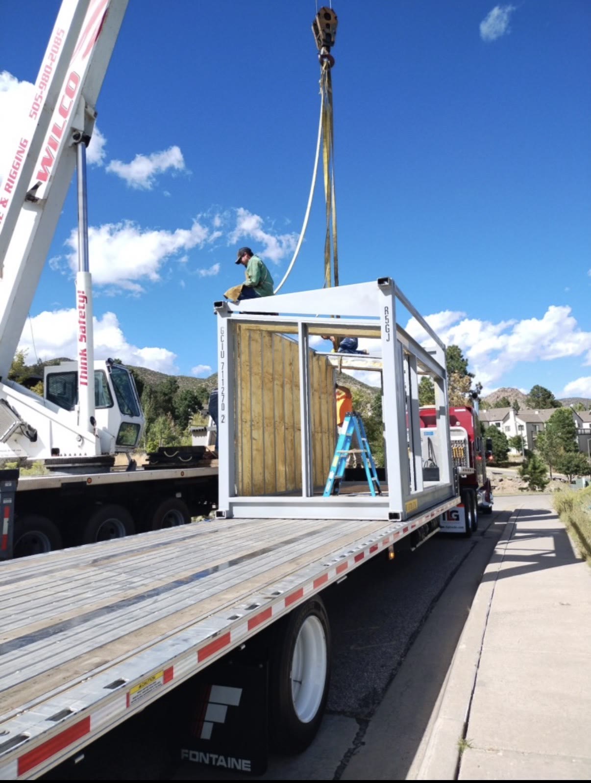 Steel bridge frame being lifted off a flatbed by crane, built by Infinity Builders in New Mexico