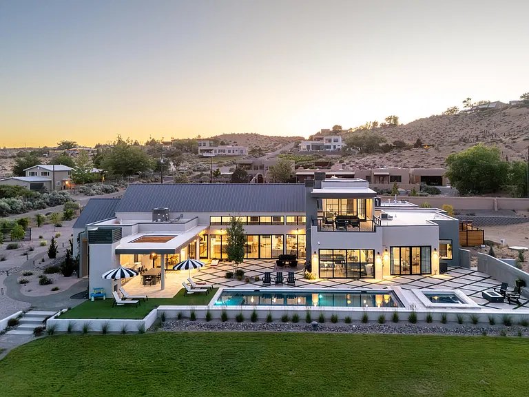 Aerial view at dusk of a Corrales, NM custom home with pool, spa, and paver courtyard, built by Infinity Builders