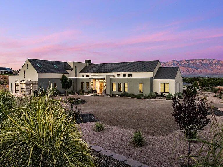 Modern farmhouse custom home in Corrales, NM at sunset with the Sandia Mountains behind, built by Infinity Builders