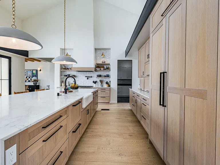 Quartz kitchen island with light oak cabinetry and farmhouse sink in a Corrales, NM custom home by Infinity Builders