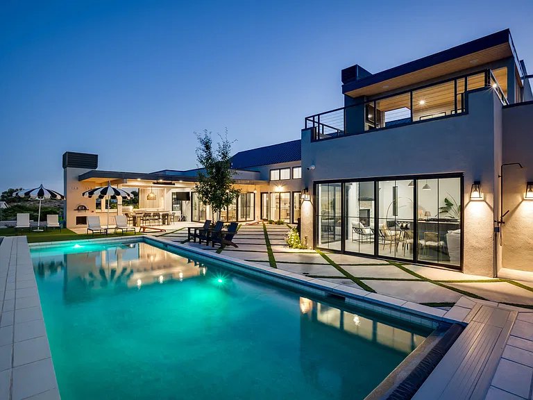 Pool and glass walls of a Corrales, NM custom home at twilight, built by Infinity Builders
