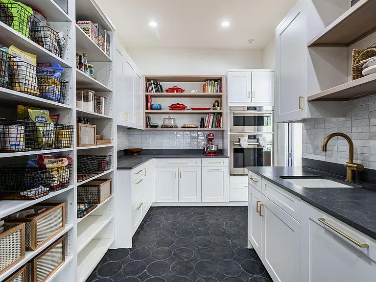 Walk-in scullery pantry with wall ovens, brass prep sink, and open shelving in a Corrales, NM custom home by Infinity Builders