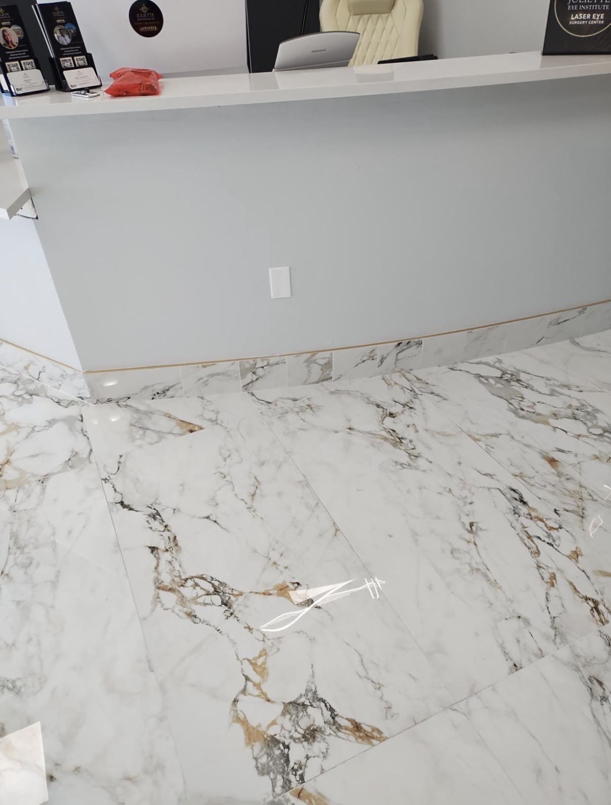 Polished marble floor tile with gold veining at an eye doctor’s office reception desk, built by Infinity Builders in New Mexico