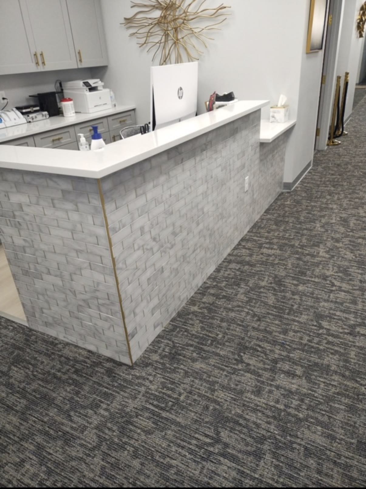 Eye doctor’s office front desk wrapped in marble subway tile with a quartz top, built by Infinity Builders in New Mexico