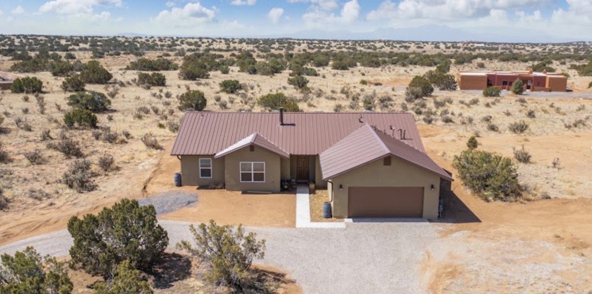 Aerial view of a high-desert ranch home with metal roof