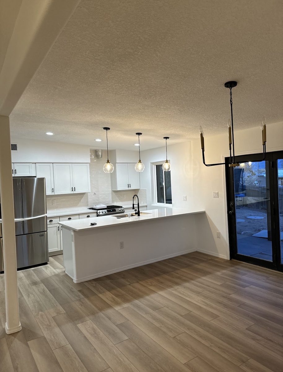 Open kitchen and dining space with pendant lights and wide-plank flooring, built by Infinity Builders in New Mexico
